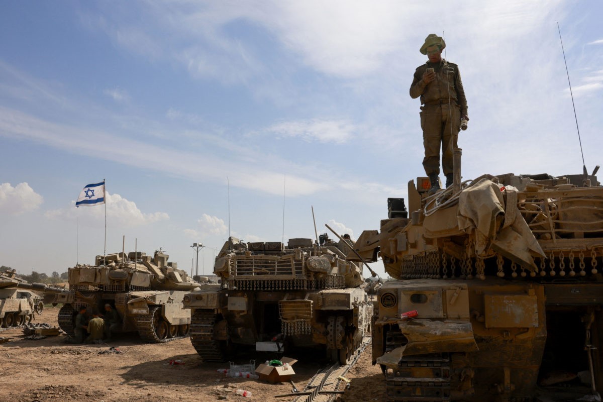 An Israeli soldier checks a mobile atop a tank in a army camp near Israel’s border with the Gaza Strip on April 8, 2024, amid the ongoing conflict between Israel and the militant group Hamas. (Photo by Menahem Kahana / AFP)